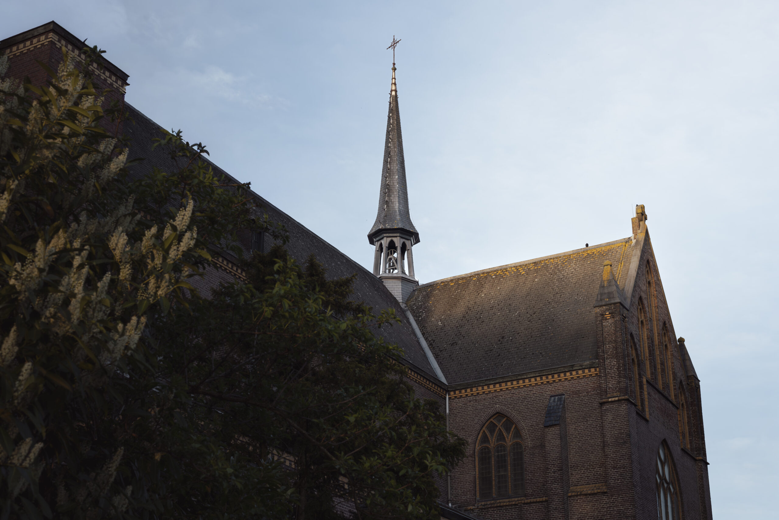 Historic brick church and its spire beneath a blue sky
